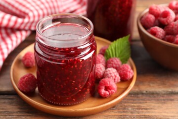 Obraz premium Tasty raspberry jam in jars and fresh berries on wooden table, closeup