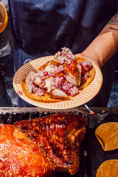 Chef holding a plate with a fresh roasted meat taco
