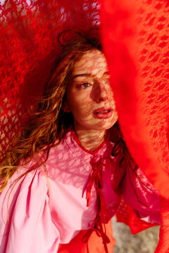 Woman with red lace shadow pattern on face