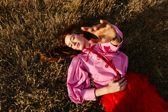 Woman relaxing in field reaching for sunlight