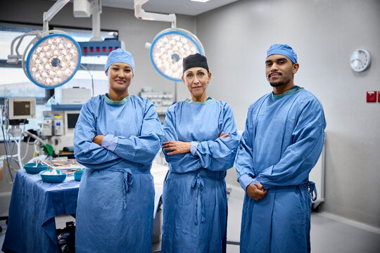 Three surgeons stand confidently in operating room