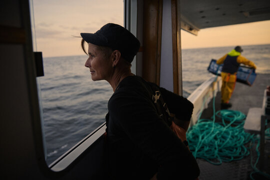 A female boat captain navigates waters at sunset near the coast