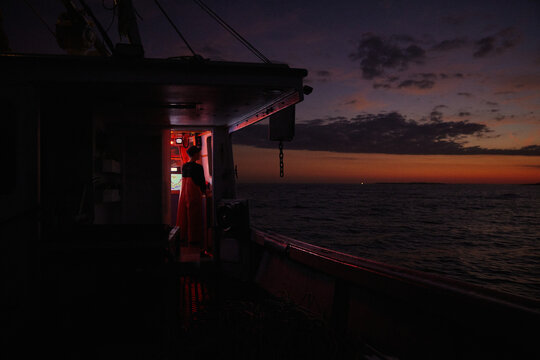 Fishing boat at sunset with crew member by the cabin door