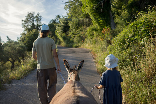 Father and child walking with donkey 
