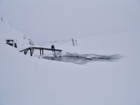 Winter Skier Sitting on a Wooden Bridge Taking Break