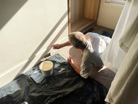 Homeowner Painting Skirting Board During Home Renovation