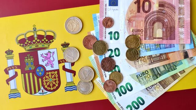 Spain, Spanish euro cash and cent coins against the background of the flag. Euro cash