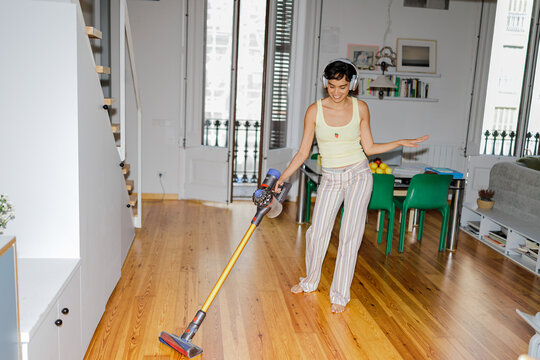 Woman enjoying cleaning routine vacuuming living room floor ugc