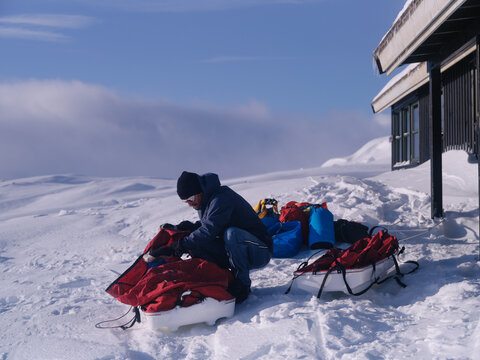 Backcountry Adventurer Preparing Gear Next To Remote Mountain Ca