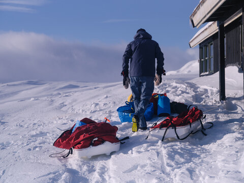 Backcountry Explorer Preparing Gear Next To Remote Mountain Hut
