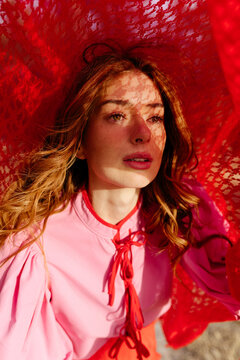 Woman covering face with red lace fabric