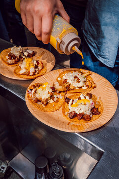 Chef squeezing yellow sauce over pork tacos 