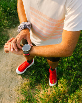 Runner Checks Watch During Morning Run in Green Park Area