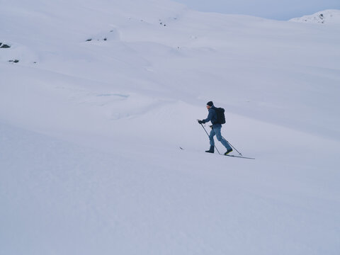 Backcountry Skier Touring Uphill on Snow Slope