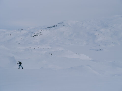 Distant Backcountry Skier Traversing Massive Snow Mountainscape