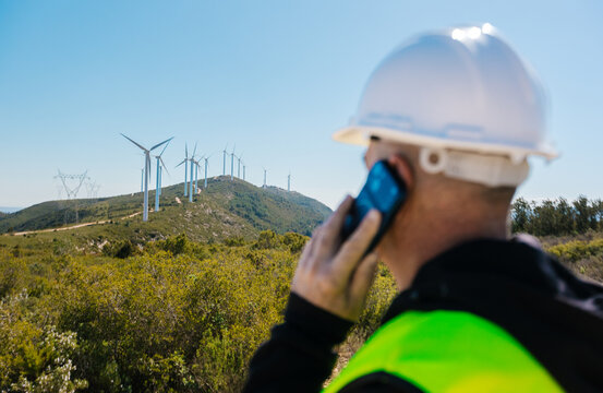 Engineer talking on phone at wind turbine field