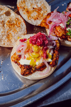 Close up of open artisan chicken sandwich with pickled red onions