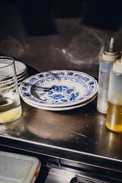 Empty ceramic plates and oil bottles on a metal kitchen counter