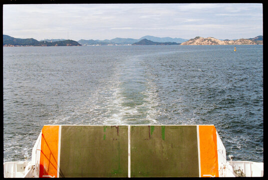 Ferry Moving Across Water With Naoshima Island n the Background, Japan