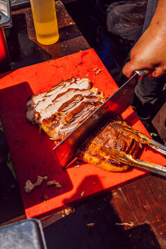 Chef carving a large piece of crispy roasted pork belly