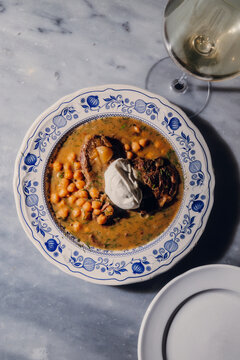 Traditional beef stew with white beans and sour cream on marble