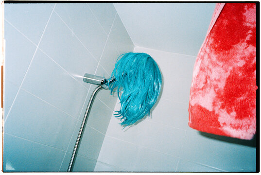 a pink towel frames a blue wig drying in the bathroom, 35mm film