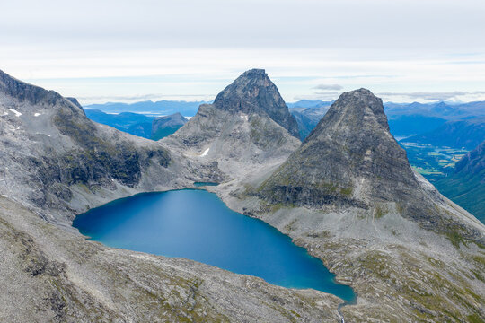 Aerial view of the deep blue Bispevannet lake nestled among the rugged, rocky mountain peaks of the Trollstigen area in Andalsnes, More og Romsdal, Norway.