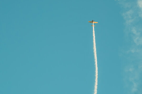 Portugal Oeiras Air Show.   small plane ascends into the blue sky with a long white trail behind it. scene captures moment on  clear day, showcasing plane's flight path against backdrop of clouds.