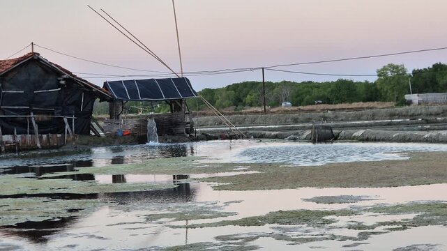 Water pump operating on traditional salt pond at dusk