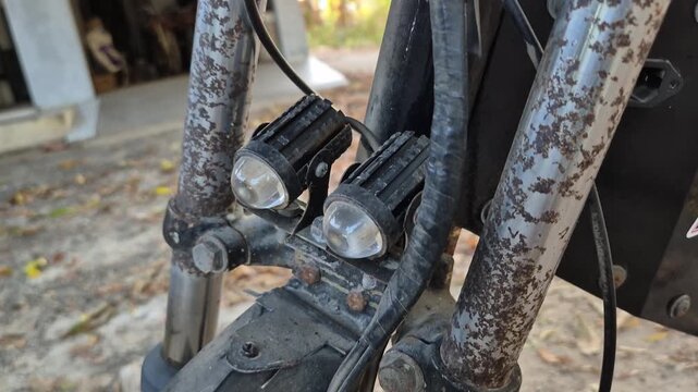 Close up of rusty front fork suspension with dual LED headlights on old custom motorcycle