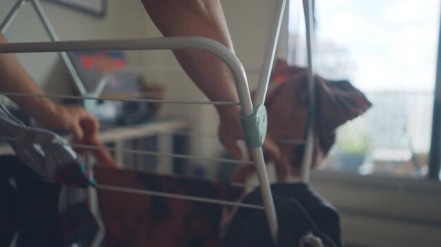 Woman hanging clothes on a folding drying rack in a city apartment