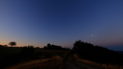 Moon on a twilight sky with stars, planets and landscape mountain silhouettes. © astrosystem