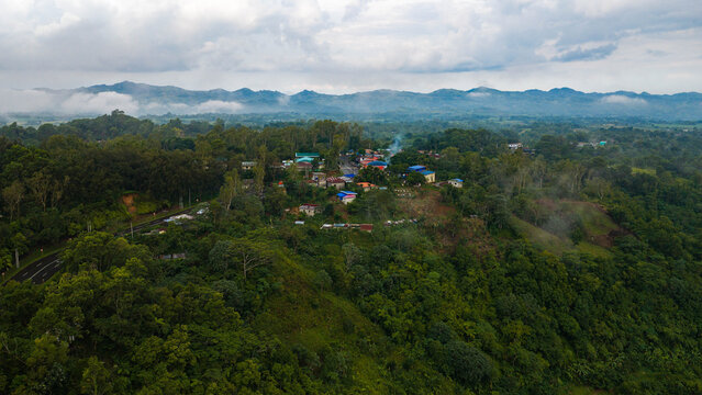 Aerial view of Don Salvador Benedicto nestled in lush green mountains, featuring a winding road and dense tropical forest under a cloudy sky in Pontevedra, Western Visayas, Philippines.