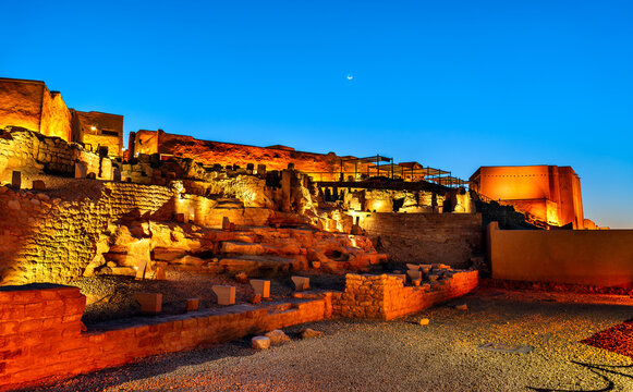 The ancient ruins of At-Turaif historical site illuminated at night under a clear blue sky in Diriyah, Saudi Arabia.