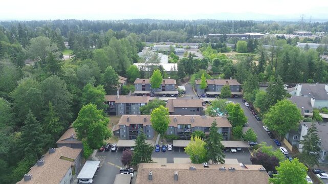 Clustered multi story apartment buildings line Pete von Reichbauer Way South, featuring dark roofing interspersed with bright foliage, reflecting regional architectural designs in Federal Way, WA