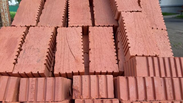 Stacked red ceramic bricks in rows at a construction site. Building material supply, masonry blocks, closeup texture background