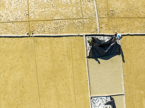 Aerial view of salt pans in Cox's Bazar with workers handling black plastic sheets to harvest salt in the Chittagong Division, Bangladesh.