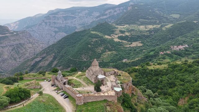 4K Drone Flight Over Tatev Monastery on a Rocky Cliff in Armenia Surrounded by Green Mountains and Dramatic Clouds.