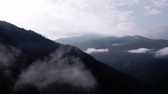 Cinematic drone flight above lush green Caucasus mountains, drifting clouds in Svaneti, Georgia. Peaceful aerial landscape for travel films, meditation, relaxation, wellness nature projects