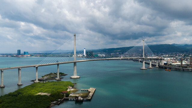 Aerial view of the Cebu-Cordova Link Expressway bridge spanning the sea with mangroves and the urban skyline of Cebu City in the background Cebu City, Central Visayas, Philippines.
