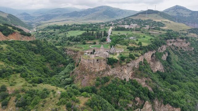 4K Drone Flight Over Tatev Monastery on a Rocky Cliff in Armenia Surrounded by Green Mountains and Dramatic Clouds.