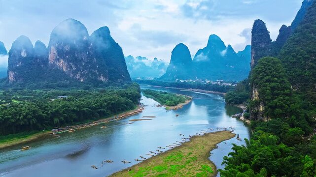 Li River winding through Guilin's limestone karst peaks, misty forested hills, bamboo groves, and traditional boats in Guangxi, China.