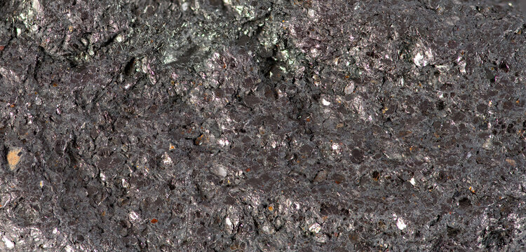 Close up view of textured rock formation showing various minerals and colors in natural surroundings
