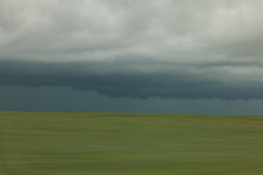 Dramatic Approaching Storm Over Open Grass Field With Dark Clouds and Motion Blur