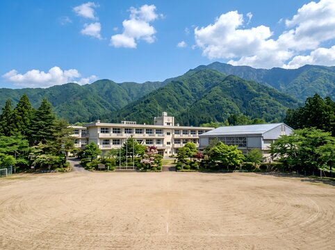 日本の新緑の山々に囲まれた青空の地方学校と校庭