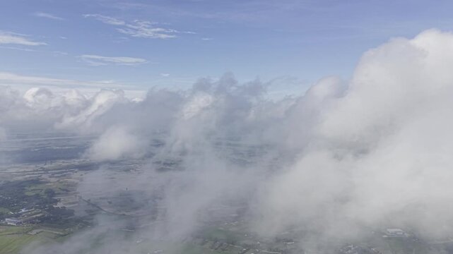 Cinematic static aerial footage captured from high altitude, with large clouds drifting continuously across the frame from one direction to another, creating a dynamic atmospheric sky scene.