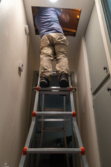 A home inspector climbing up to the attic with a ladder to inspect the attic © Devka