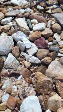 Stones in the crystal clear water of a stream or shallow body of water, viewed from above as a texture or background