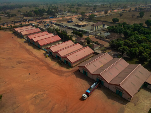 Aerial view of industrial warehouses with red roofs and a truck parked on red earth near the Abuja - Kaduna - Zaria Express Way in Kaduna, Kaduna, Nigeria.