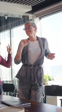 Vertical. Enthusiastic business team celebrating success, dancing together in the office, enjoying a moment of joy and camaraderie after achieving a goal
